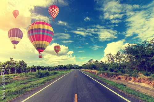 hot air balloon over a cloudy sky and open road.