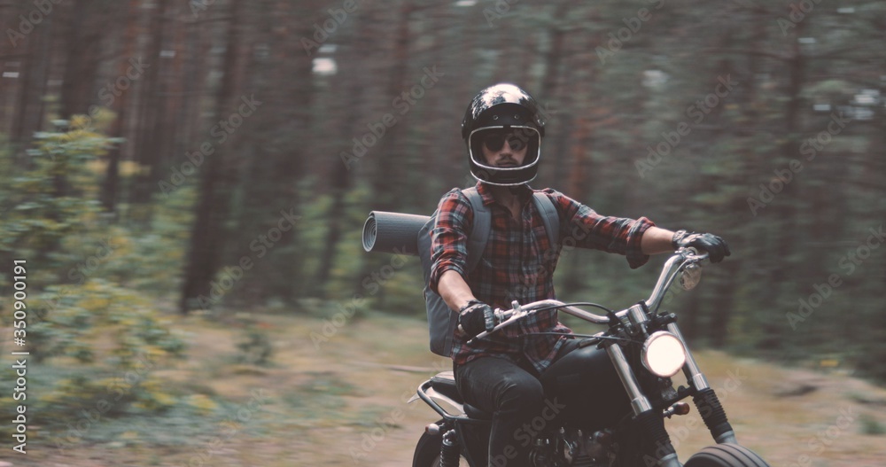 Young rider driving motorcycle on forest road