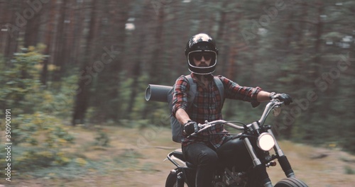 Young rider driving motorcycle on forest road