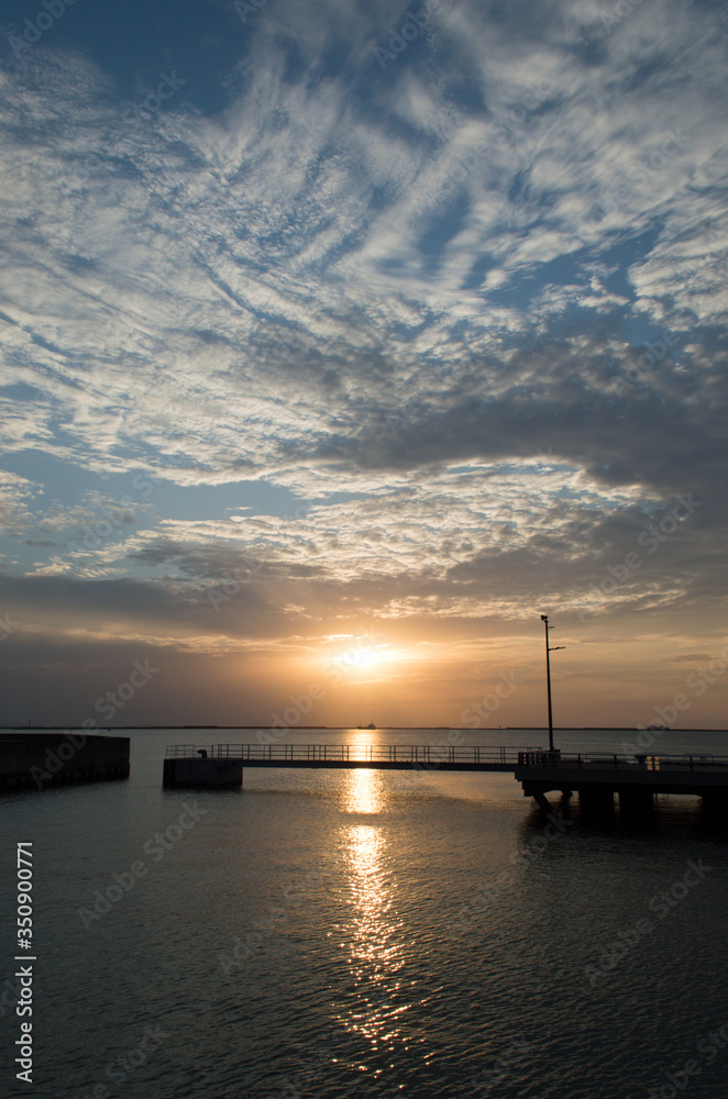 オレンジ色の夕日とシルエットの桟橋
