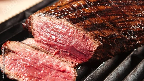 Grilled sliced beef steak on a black cutting board on the wooden table. Smoke