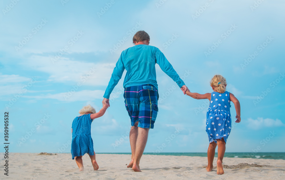 happy father and daughters play on beach