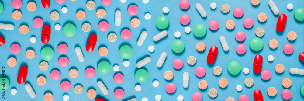 Colorful, green, red, white pills on blue background, flat lay Colorful, green, red, white pills on blue background, flat lay