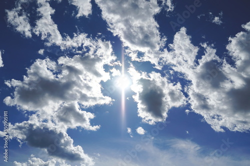 Beautiful skyscape with many cumulonimbus clouds and shiny sun in the middle