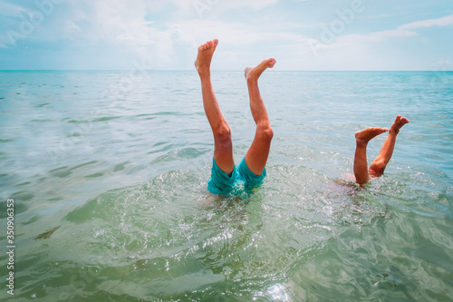 Fototapet kids making handstand in sea, kids vacation fun