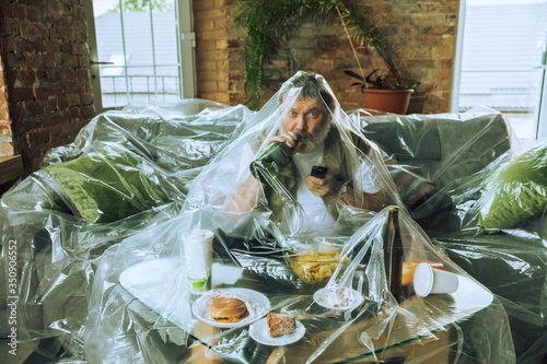 Senior man covered with plastic, eating fast food - environmental pollution by people concept. Eco campaign. We've polluted the planet so much that no longer notice it. Unhealthy, garbage, problem. photo