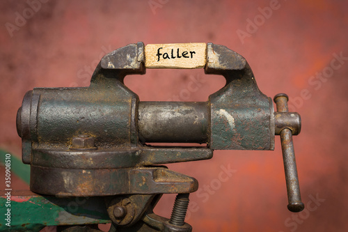 Vice grip tool squeezing a plank with the word faller photo