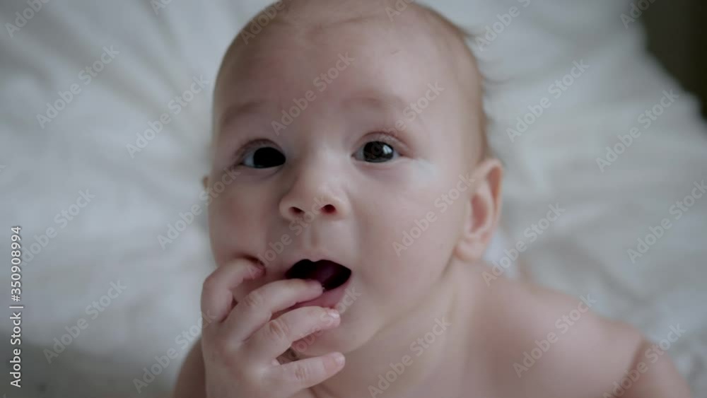 Portrait Of Newborn Baby In Diaper Looking At Camera And Sucking Fingers Portrait Of Newborn Baby In Diaper Looking At Camera And Sucking Fingers