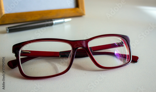 Beautiful glasses, metal pen and frame on a white table. Business concept.