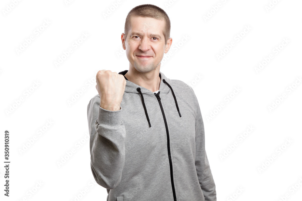 smiling joyful man, wearing a hooded sports jacket, holds his fist, a gesture OK okey good. Isolated smiling joyful man, wearing a hooded sports jacket, holds his fist, a gesture OK okey good. Isolated