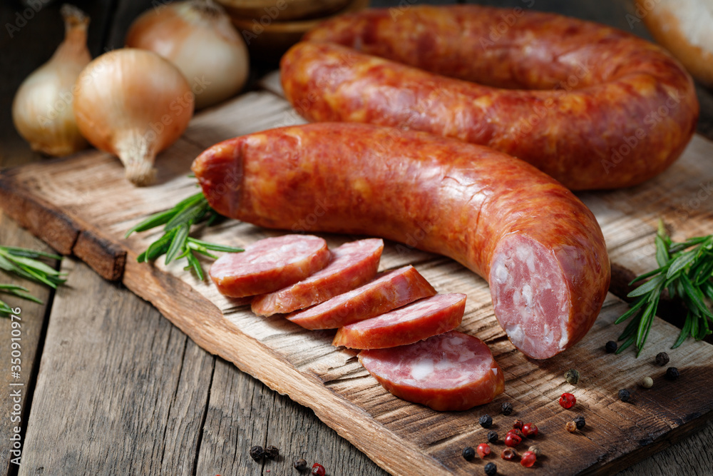 Smoked sausage on a wooden table. Rustic style. - obrazy, fototapety, plakaty 