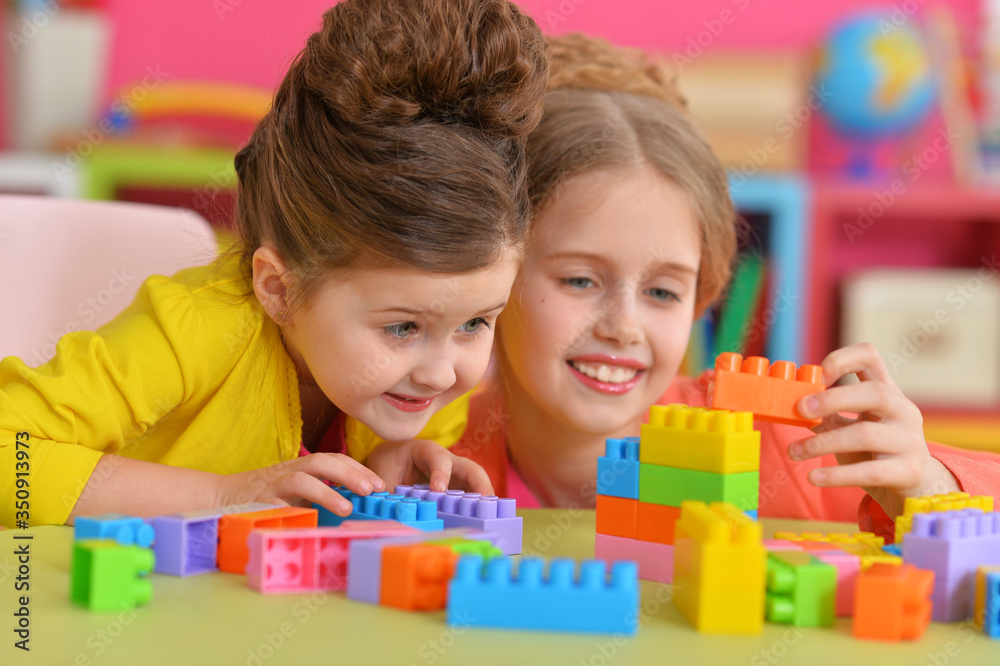 Two little girls playing with colorful plastic blocks