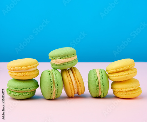 stack of yellow and green round almond flour cakes macarons with cream on a blue background