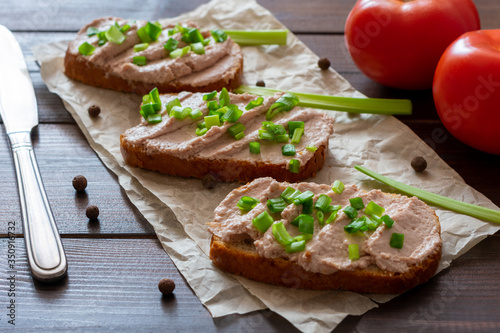 Sandwich with pate with green onion on a wooden background. Sandwich on crumpled paper with herbs.