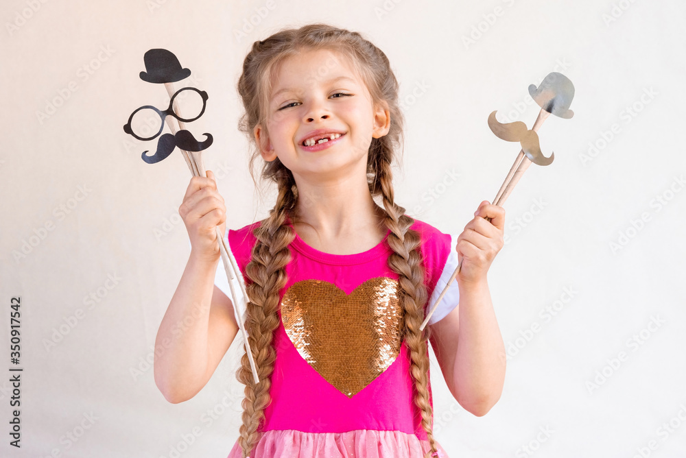A happy little girl holds masquerade masks in her hands. A happy little girl holds masquerade masks in her hands.