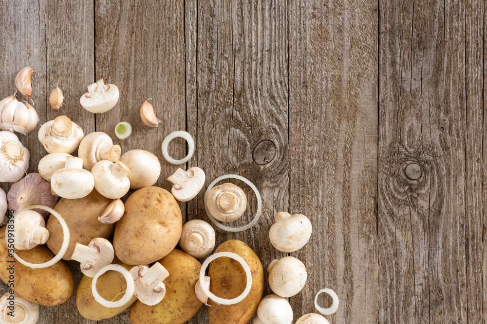 Mushrooms, potatoes and onion rings with garlic on a wooden background. Template for text, top view.