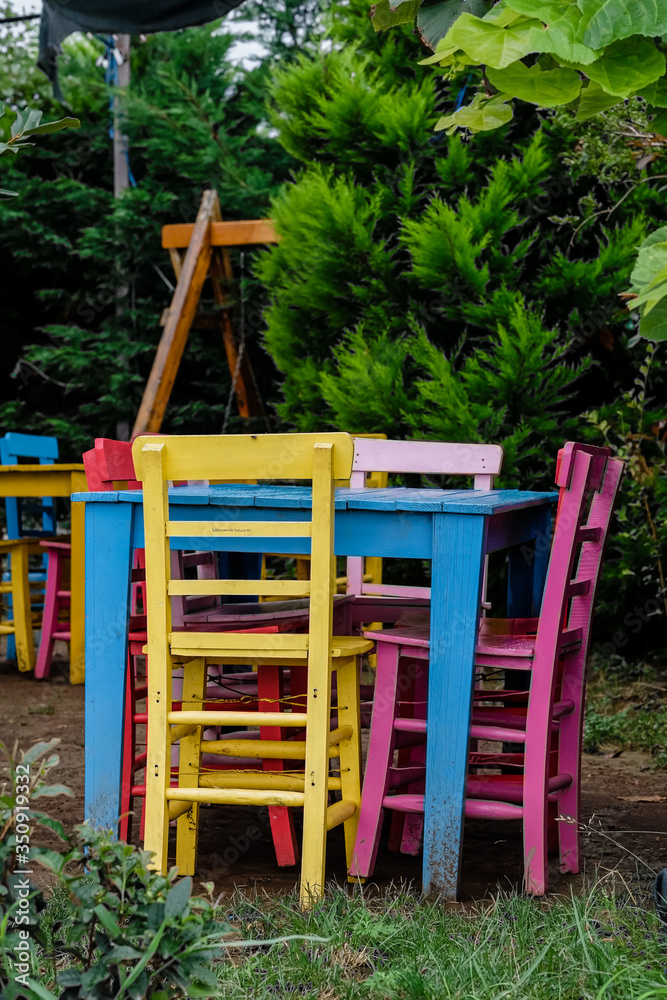 multi-colored wooden table and chairs in the summer garden at the cottage multi-colored wooden table and chairs in the summer garden at the cottage