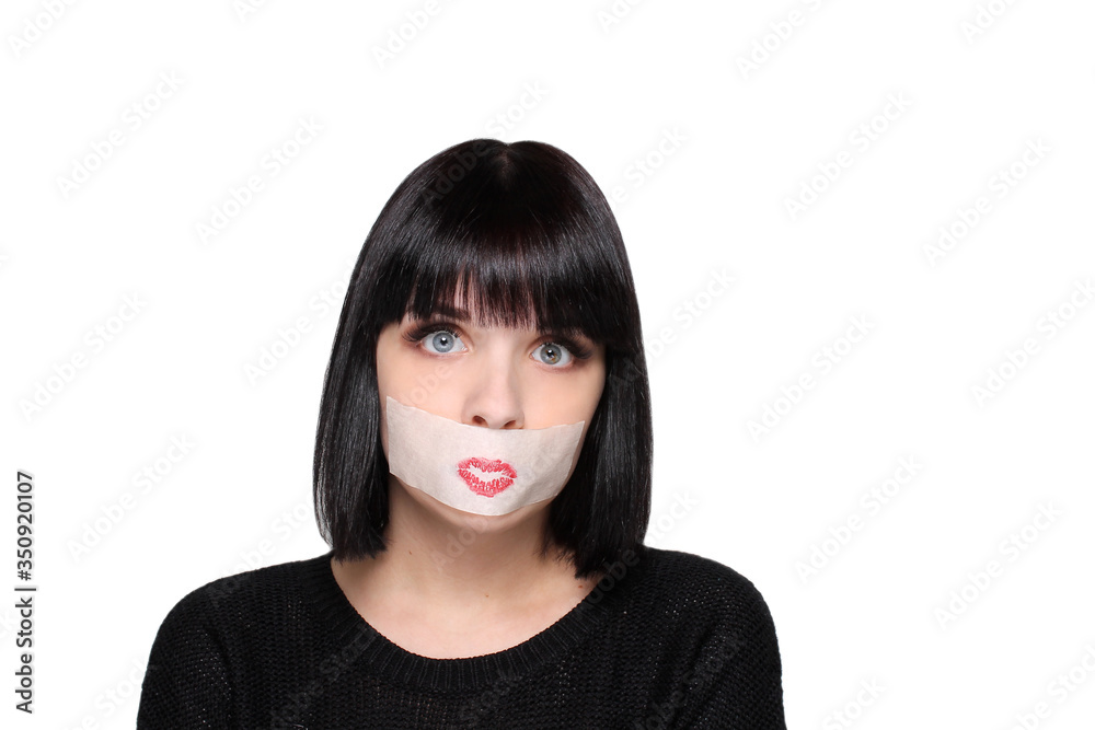 Young beautiful girl with a sticky tape taped over her mouth and a painted kiss on her face. Girl draws a kiss on her face Young beautiful girl with a sticky tape taped over her mouth and a painted kiss on her face. Girl draws a kiss on her face