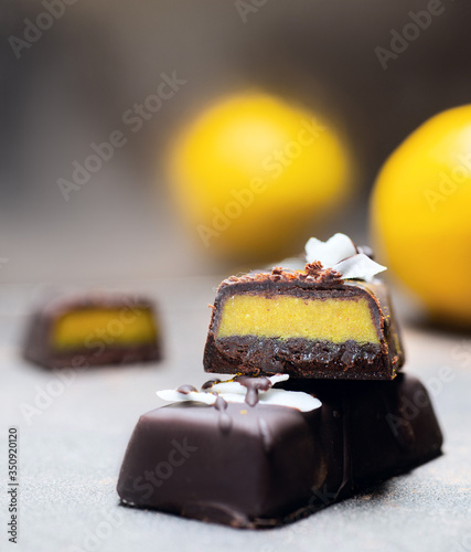 Chocolate citrus candies without sugar and lemons on the background. Raw vegan chocolate candies. Lactose free candies. Gluten free candies. Without artificial dyes chocolate.