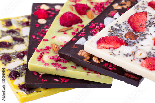 Bars of multicolor  chocolate with sublimated berries, coconut nuts and seeds on the white background. Raw vegan chocolate. Lactose free chocolate. Gluten free chocolate. Without artificial dyes. photo