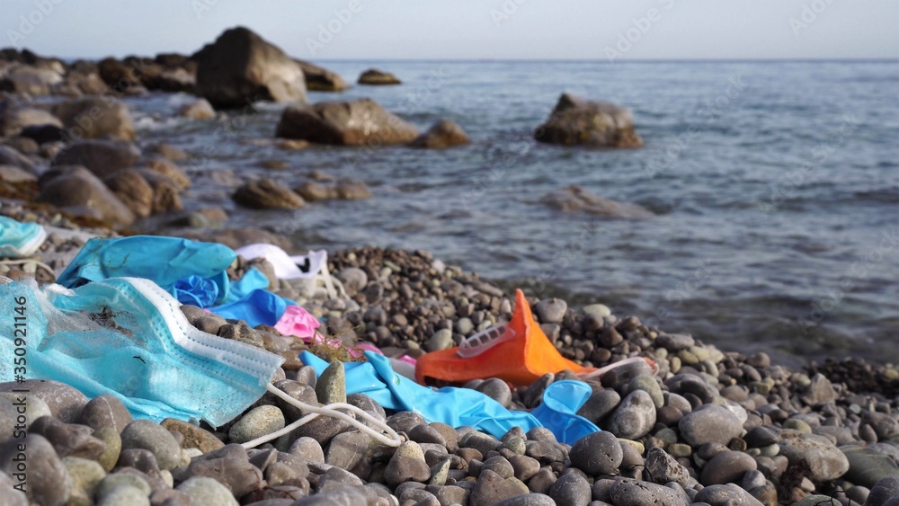 Waste during COVID-19. Discarded to ocean coronavirus single-use face masks and used latex gloves. Environmental and ocean plastic pollution Waste during COVID-19. Discarded to ocean coronavirus single-use face masks and used latex gloves. Environmental and ocean plastic pollution