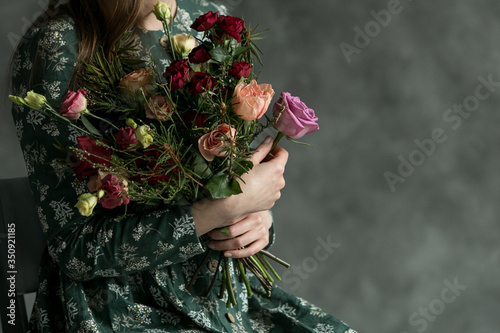 The young woman in the green dress with beautiful bouquet from roses. Hands with amazing flowers.