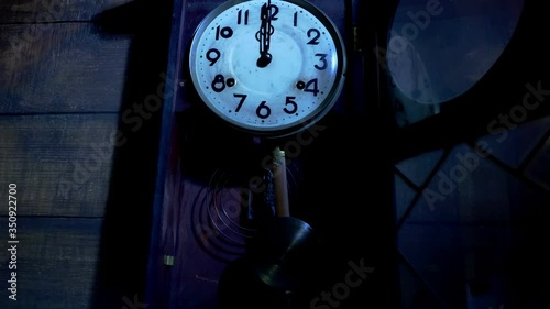 Close up of antique pendulum wall clock on midnight