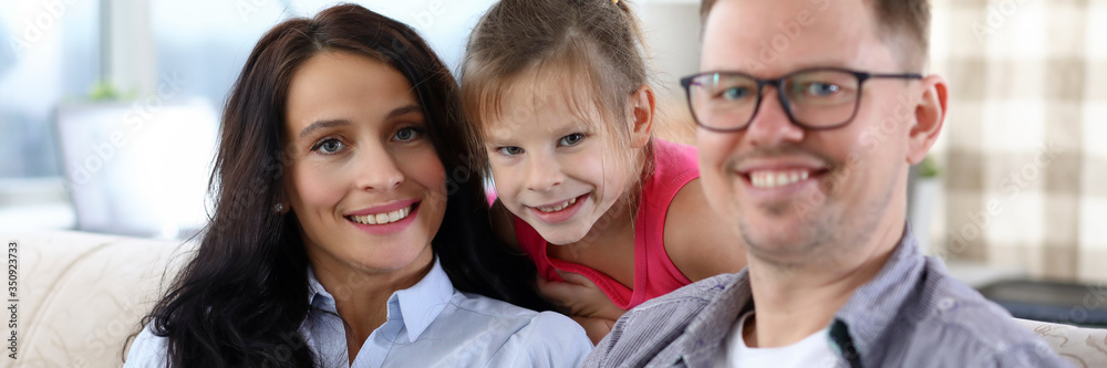 Happy smiling family sitting on couch looking at camera Happy smiling family sitting on couch looking at camera
