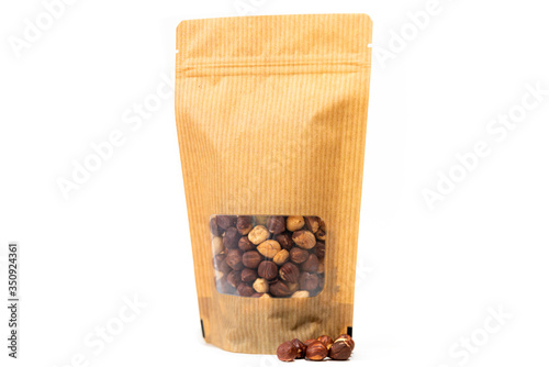 yellow food packaging in paper, plain doypack standup bag filled with hazelnut with window and zipper on white background photo