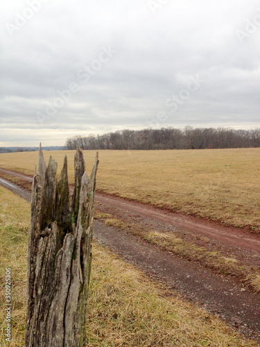 Old wooden fence post landscape country farm with cloudy sky and country road