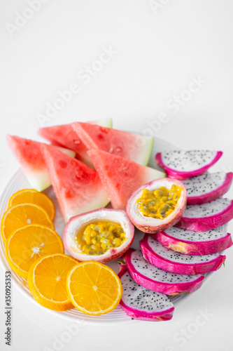 White plate of sliced fruit. Fresh fruits and vitamins. Still life colored summer fruits.