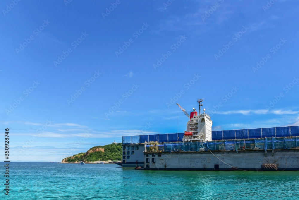 Shipyard accommodation bridge deck of Cargo ship during repair in floating dry dock with safety life boat exhaust pipe gas on the blue-sky blue sea Thailand
