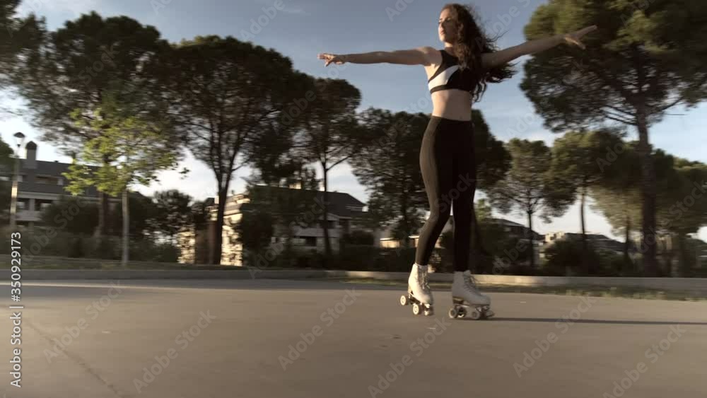 Pretty skater girl skating on roller skates at sunset