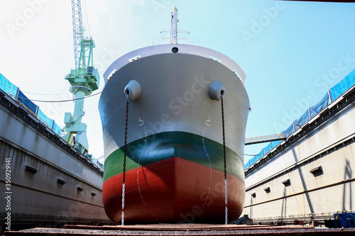 Prow ship, Cargo ship Moored repair in floating dry dock, bollard on the front of Bulbous bow in shipyard during maintenance sandblasting and planting both anchor chain hanging forward 