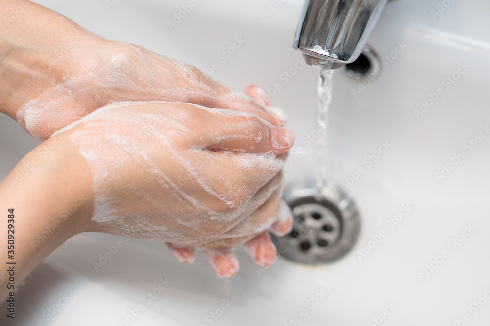 Fototapeta premium thorough hand washing with soap in the sink, self-disinfection, skin treatment with foam and water, antibacterial and antiviral use, close-up 