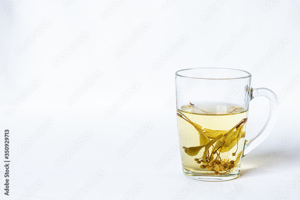 In a transparent mug tea with linden flowers on a white background In a transparent mug tea with linden flowers on a white background