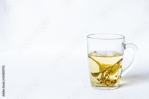 In a transparent mug tea with linden flowers on a white background