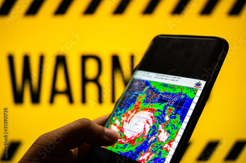 Mobile phone logged into photo of cyclone with warning background
