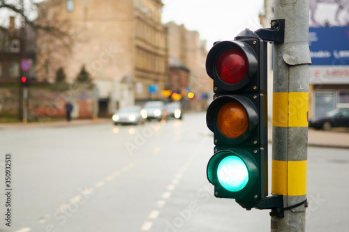 Green traffic light on a city street. A woman is waiting at a pedestrian crossing.