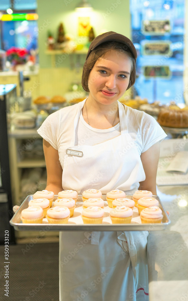 Smiling shy girl with cupcakes at the tray reflex