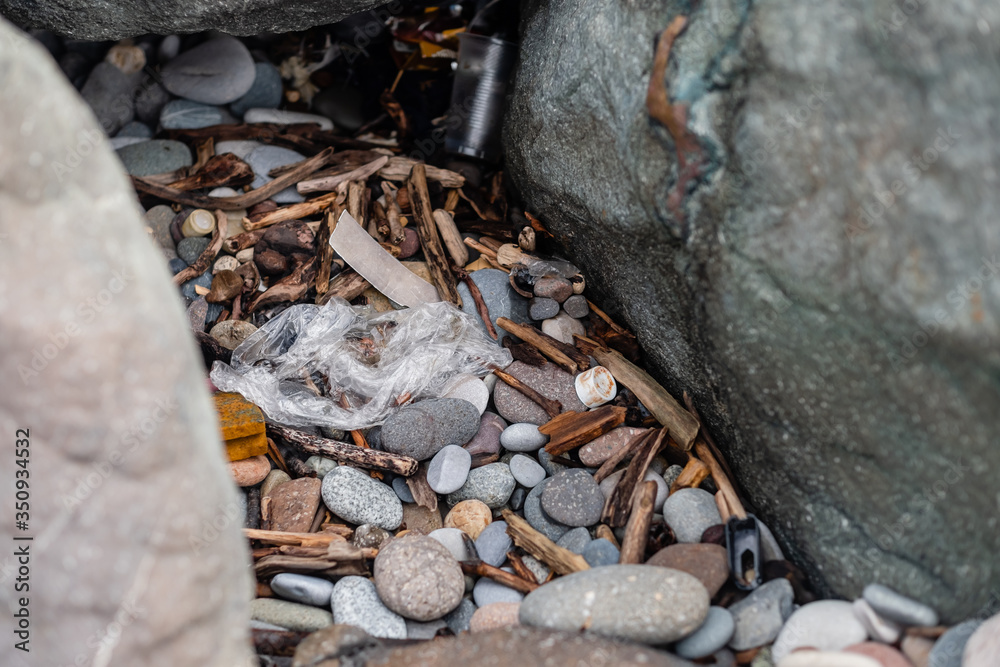 garbage on the beach among the rocks. stop plastic garbage on the beach among the rocks. stop plastic
