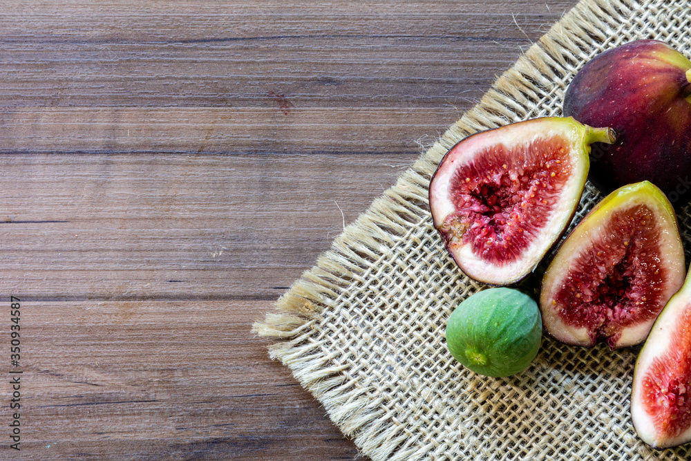 Top view of figs, green leaves on rustic wooden background