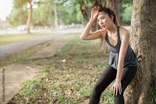 An Asian woman sat and wiped away the sweat after running in the park.