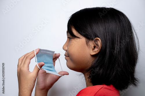 Asian girl on a white background wearing a face mask to protect and prevent the spread of the virus. Coronavirus disease 2019 (COVID-19) outbreak.