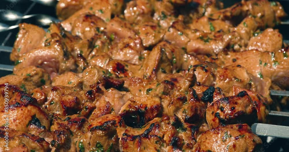 Appetizing delicious fried pieces of meat on skewers are roasted on a large grill in the open air. The chef prepares a barbecue. Close up, 4k. Appetizing delicious fried pieces of meat on skewers are roasted on a large grill in the open air. The chef prepares a barbecue. Close up, 4k.
