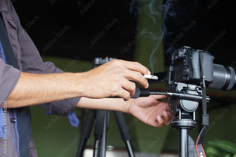 Man holding a cigarette in hand while working. Man holding a cigarette in hand while working.