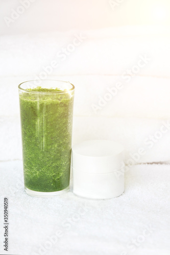 Green smoothie juice of vegetables and face cream in a white jar. The concept of cleansing the body of toxins. Organic energy eating. Athlete vitamic shake. Health lifestyle