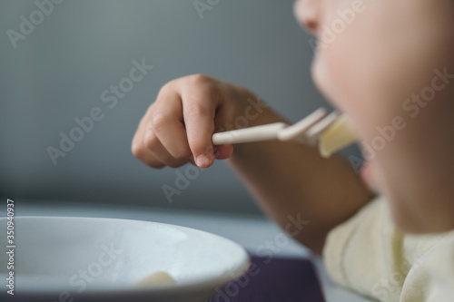 cropped view of little boy having dinner while eating pasta with fork