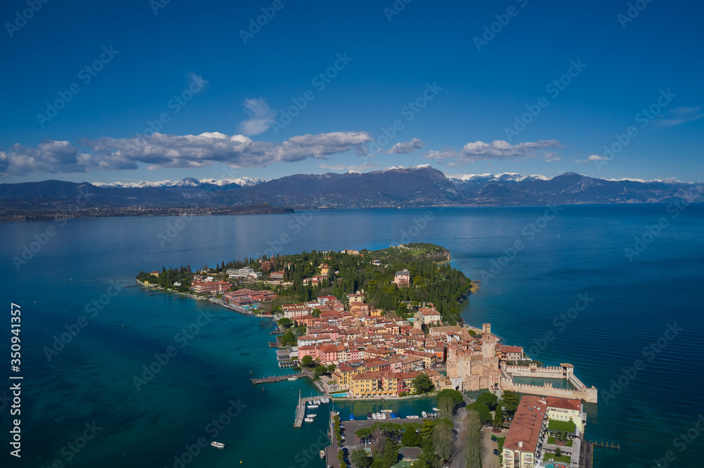Sirmione town, Lake Garda, Italy. Aerial view of Sirmione. The historical part of the city.  In the background mountains in the snow and blue sky. Aerial panorama