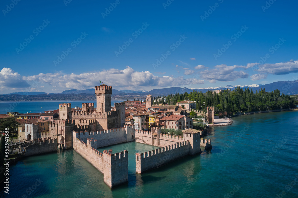 Fototapeta Sirmione Castle, Lake Garda, Italy. Aerial view of Sirmione. In the background mountains in the snow and blue sky.